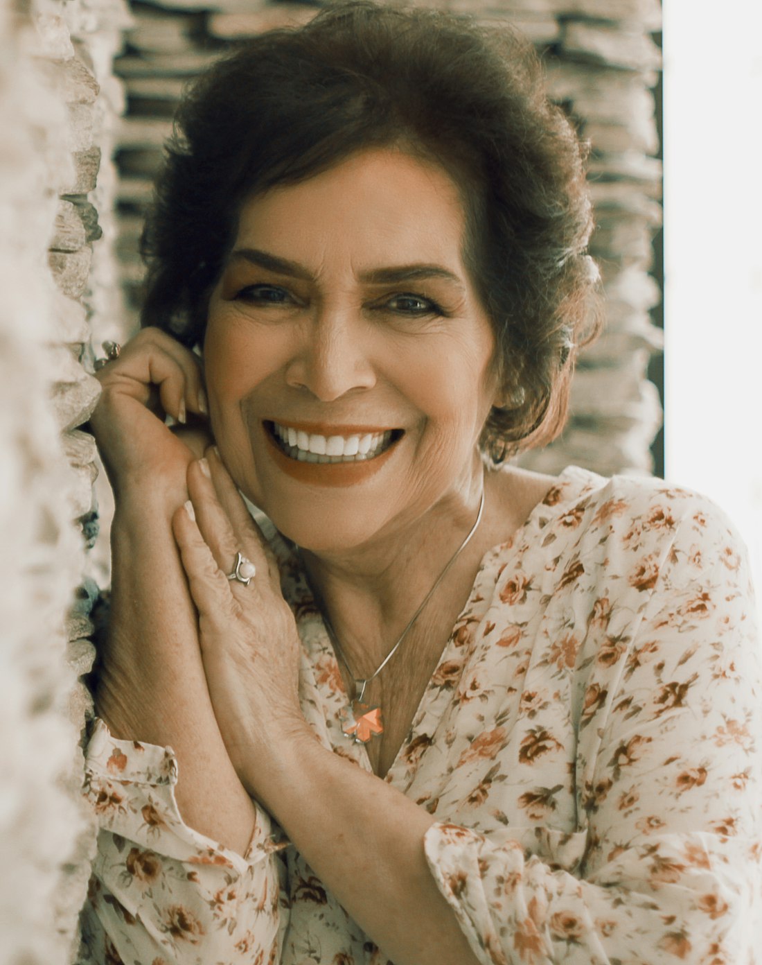 Styling imagery: a radiant older woman in a floral blouse wearing her pearl ring and pendant