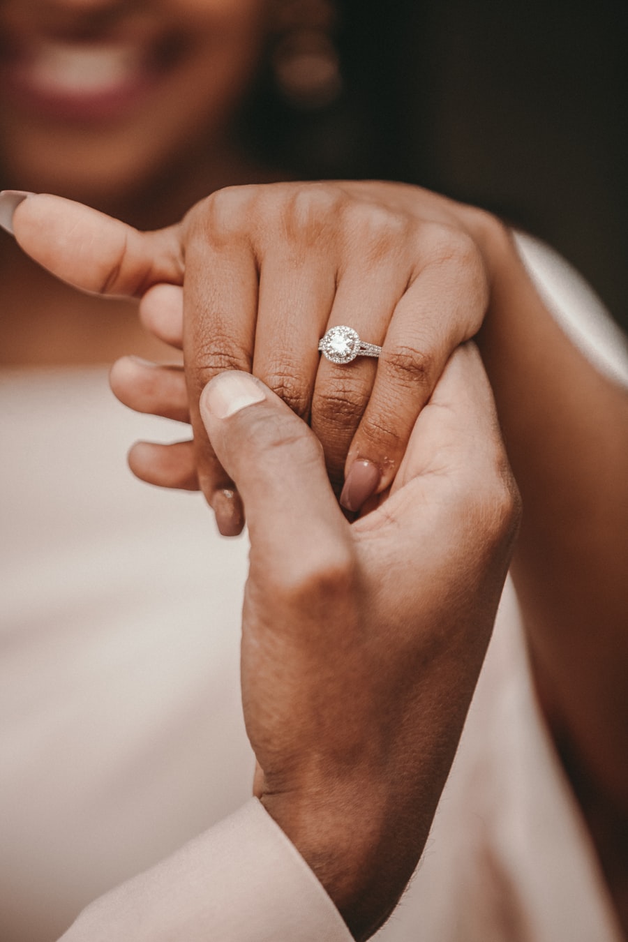 Styling imagery: a smiling woman showing her halo engagement ring while holding hands