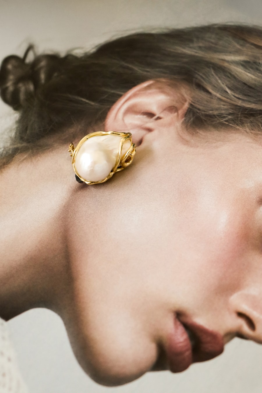 Styling imagery: a baroque pearl and gold earring worn close-up