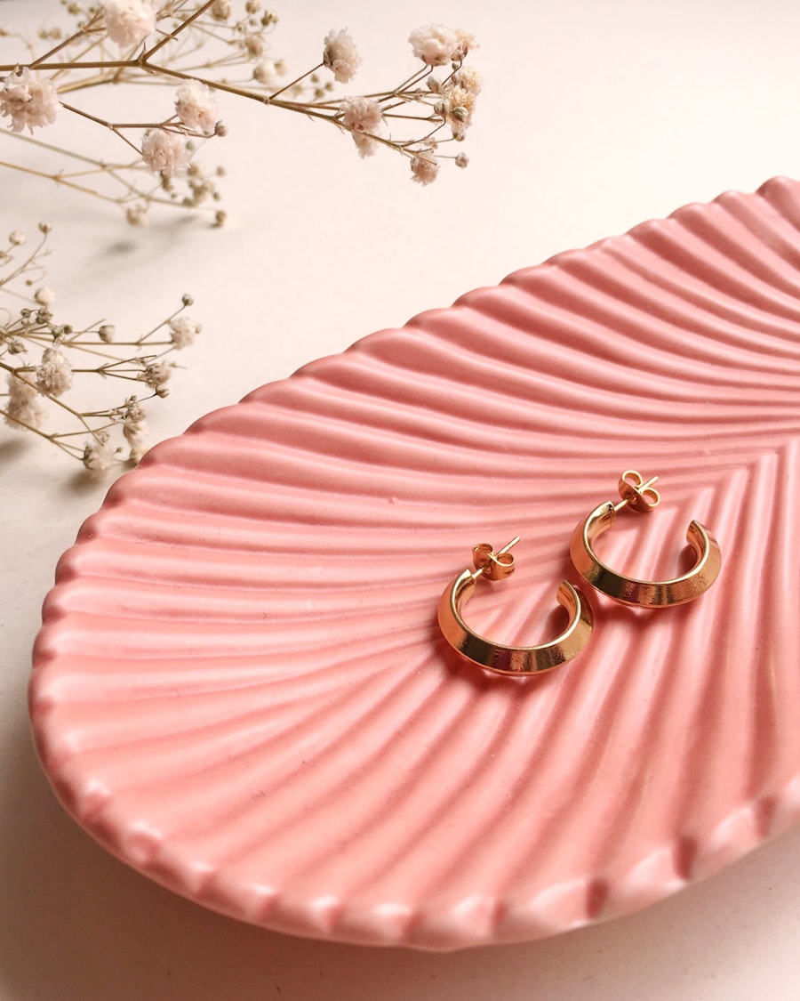 Styling imagery: gold hoops on a pink shell dish with sprigs of dried blossom