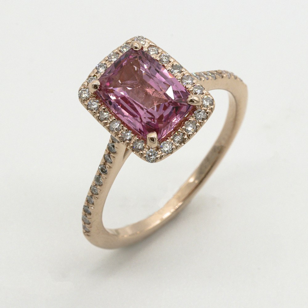 Styling imagery: a pink gemstone ring with a diamond halo in rose gold