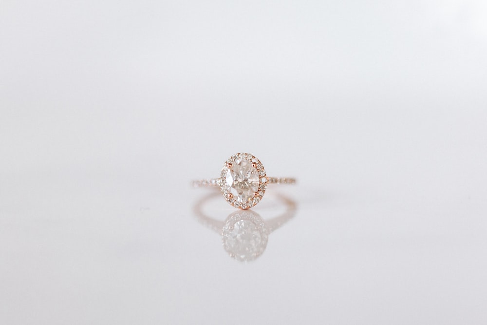 Styling imagery: a rose gold oval halo ring on a white surface